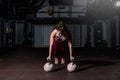 Young strong fit sweaty muscular girl with big muscles doing push ups on two big old heavy kettlebells with her hands for hard cor Royalty Free Stock Photo