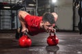 Young strong fit sweaty muscular man with big muscles doing push ups on two big old heavy kettlebells Royalty Free Stock Photo