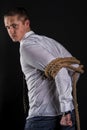 Young beautiful man tied up with rope stands sideways Royalty Free Stock Photo