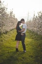 Young strong love between two young people standing under apple trees. Candid portrait of a couple in casual clothes. Affection of Royalty Free Stock Photo