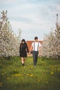 Young strong love between two young people walking under apple trees. Candid portrait of a couple in casual clothes. Affection of Royalty Free Stock Photo
