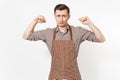 Young strong man chef or waiter in striped brown apron, shirt showing biceps, muscles isolated on white background. Male