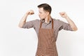 Young strong man chef or waiter in striped brown apron, shirt showing biceps, muscles isolated on white background. Male