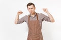 Young strong man chef or waiter in striped brown apron, shirt showing biceps, muscles isolated on white background. Male