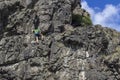 Young strong man climber hangs on a cliff or rock wall. Climbing, mountaineering concept