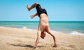 Young strong man in excellent physical shape handstands on the beach near the sea Royalty Free Stock Photo