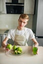 Young strong man having light breakfast.Apple juice in the kitchen. Fresh fruits and healthy food Royalty Free Stock Photo