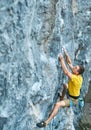 Young strong man rock climber in yellow t-shirt, climbing on a cliff Royalty Free Stock Photo