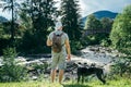 Young strong man stays near mountains river with dog and looking for the view Royalty Free Stock Photo