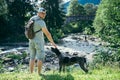 Young strong man stays near mountains river with dog and looking for the view Royalty Free Stock Photo