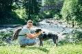 Young strong man stays near mountains river with dog and looking for the view Royalty Free Stock Photo