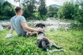 Young strong man stays near mountains river with dog and looking for the view Royalty Free Stock Photo