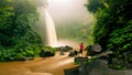 Young strong man traveler enjoy spectacular morning view, beautiful Nungnung Waterfall Royalty Free Stock Photo