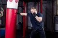 Young strong mixed martial arts fighter delivers strong hand punch to punching bag. Active exercise in gym. Royalty Free Stock Photo