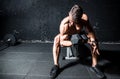 Young strong sweaty man biceps workout training with heavy dumbbell in the gym dark image with shadows real people Royalty Free Stock Photo