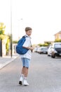 Young student boy with backpack looking at the camera while walking on the street. Royalty Free Stock Photo