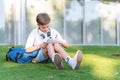 Young student boy doing homework in notebook while sitting on the grass outdoors. Royalty Free Stock Photo