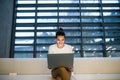 Young student or businesswoman sitting on desk in room in a library or office, using laptop. Royalty Free Stock Photo