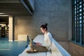 Young student or businesswoman sitting on desk in room in a library or office, using laptop. Royalty Free Stock Photo