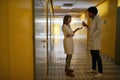 A young student couple is enjoying chatting at a break in the university building hallway. Institution, hallway, university,