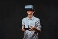 Young student dressed in a white shirt using virtual reality glasses and holds a quadcopter control remote. Royalty Free Stock Photo
