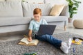 Young student ginger boy with laptop doing homework at home Royalty Free Stock Photo