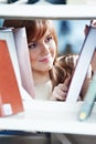 Young student girl at book shelf