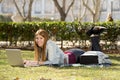 Young student girl lying on park grass with computer studying or surfing on internet Royalty Free Stock Photo