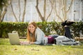 Young student girl lying on park grass with computer studying or surfing on internet Royalty Free Stock Photo