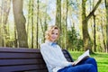 Young student girl in shirt sitting with a book in her hand in a green park, science and education, reading Royalty Free Stock Photo