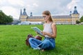 Young student girl sitting on grass, educational building background