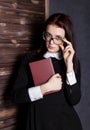 Young student in glasses with books in hand, mysteriously looking at the camera