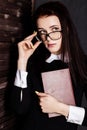 Young student in glasses with books in hand, mysteriously looking at the camera