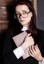 Young student in glasses with books in hand, mysteriously looking at the camera