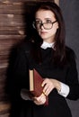 Young student in glasses with books in hand, mysteriously looking at the camera