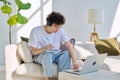 Young student guy in headphones sitting at home on with laptop taking notes Royalty Free Stock Photo