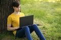 A young student guy sits on the lawn and holds a laptop in his hands Royalty Free Stock Photo