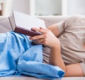 Young student man preparing for college exams in bed with book Royalty Free Stock Photo