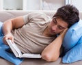 Young student man preparing for college exams in bed with book Royalty Free Stock Photo