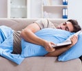 Young student man preparing for college exams in bed with book Royalty Free Stock Photo