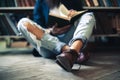 Young student man sitting on floor, reading book in library Royalty Free Stock Photo