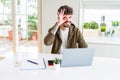 Young student man using computer laptop and notebook with happy face smiling doing ok sign with hand on eye looking through Royalty Free Stock Photo