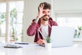 Young student man using computer laptop and notebook with happy face smiling doing ok sign with hand on eye looking through Royalty Free Stock Photo