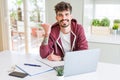 Young student man using computer laptop and notebook pointing and showing with thumb up to the side with happy face smiling Royalty Free Stock Photo