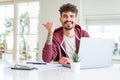 Young student man using computer laptop and notebook pointing and showing with thumb up to the side with happy face smiling Royalty Free Stock Photo