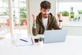 Young student man using computer laptop and notebook screaming proud and celebrating victory and success very excited, cheering Royalty Free Stock Photo