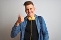 Young student man wearing denim shirt backpack headphones over isolated white background happy with big smile doing ok sign, thumb Royalty Free Stock Photo