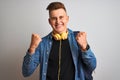 Young student man wearing denim shirt backpack headphones over isolated white background screaming proud and celebrating victory Royalty Free Stock Photo