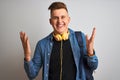 Young student man wearing denim shirt backpack headphones over isolated white background very happy and excited, winner expression Royalty Free Stock Photo