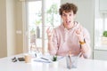 Young student man writing on notebook and studying crazy and mad shouting and yelling with aggressive expression and arms raised